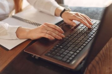 A woman sits at a desk on a laptop engaging in a business English course online