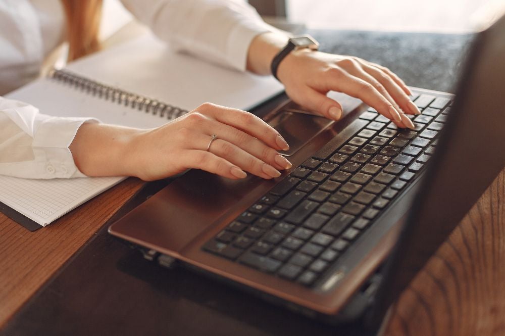 A woman sits at a desk on a laptop engaging in a business English course online