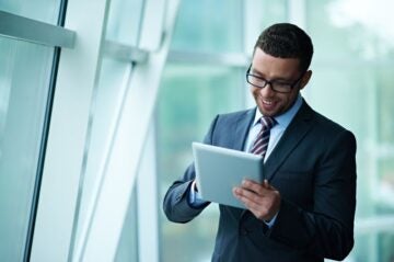 A young man in a suit engages in business English training on his mobile tablet