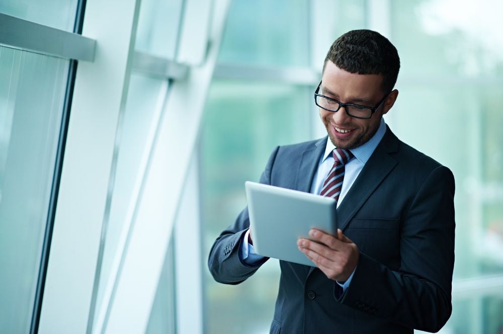 A young man in a suit engages in business English training on his mobile tablet