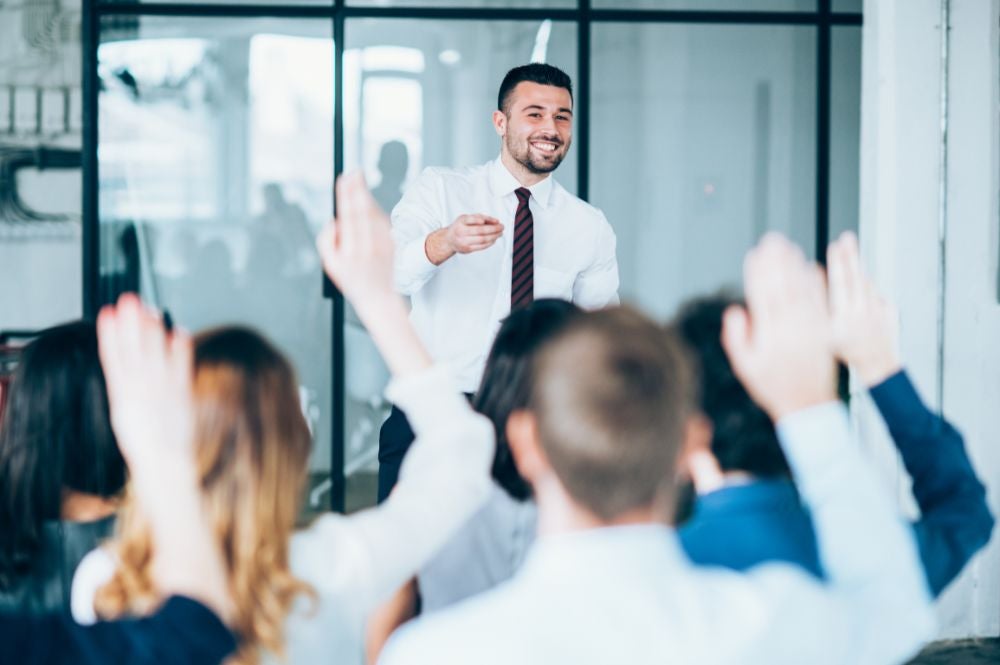 A man stands in front of a corporate group during a corporate english training language training session