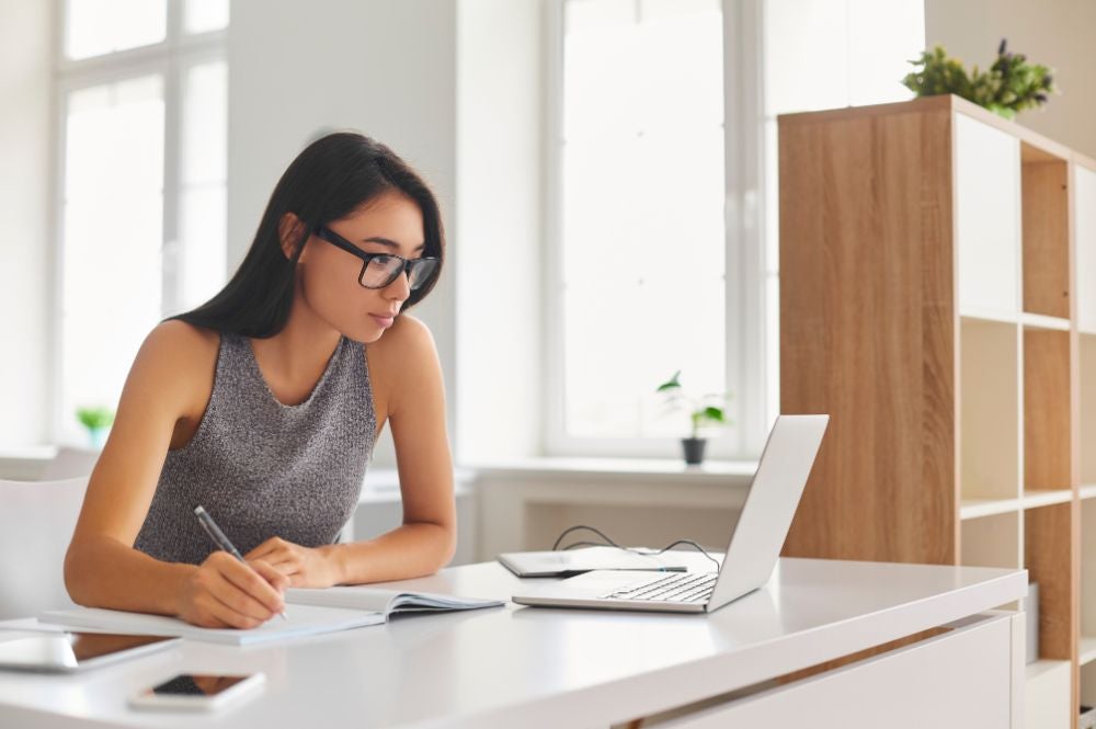 A young woman on her laptop engages on a business English online course.