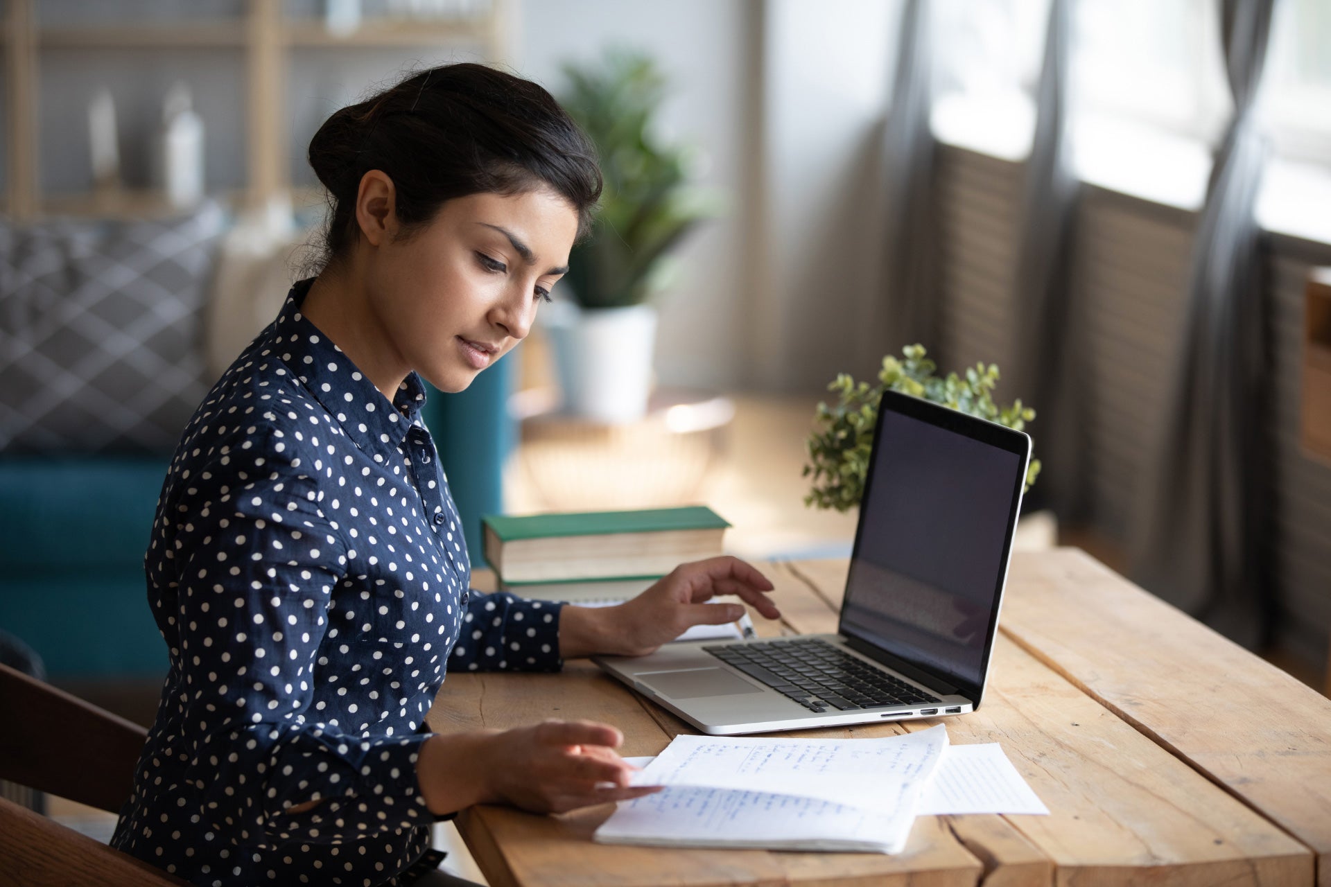 Young woman attending an online course and taking notes