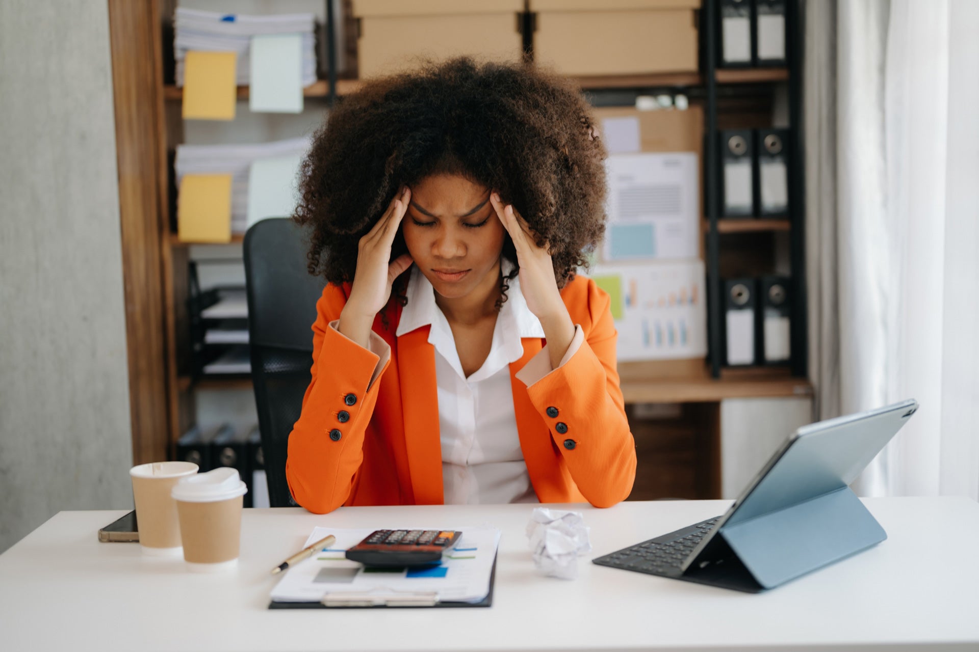 A woman at her desk in front of a laptop looking sad or unmotivated