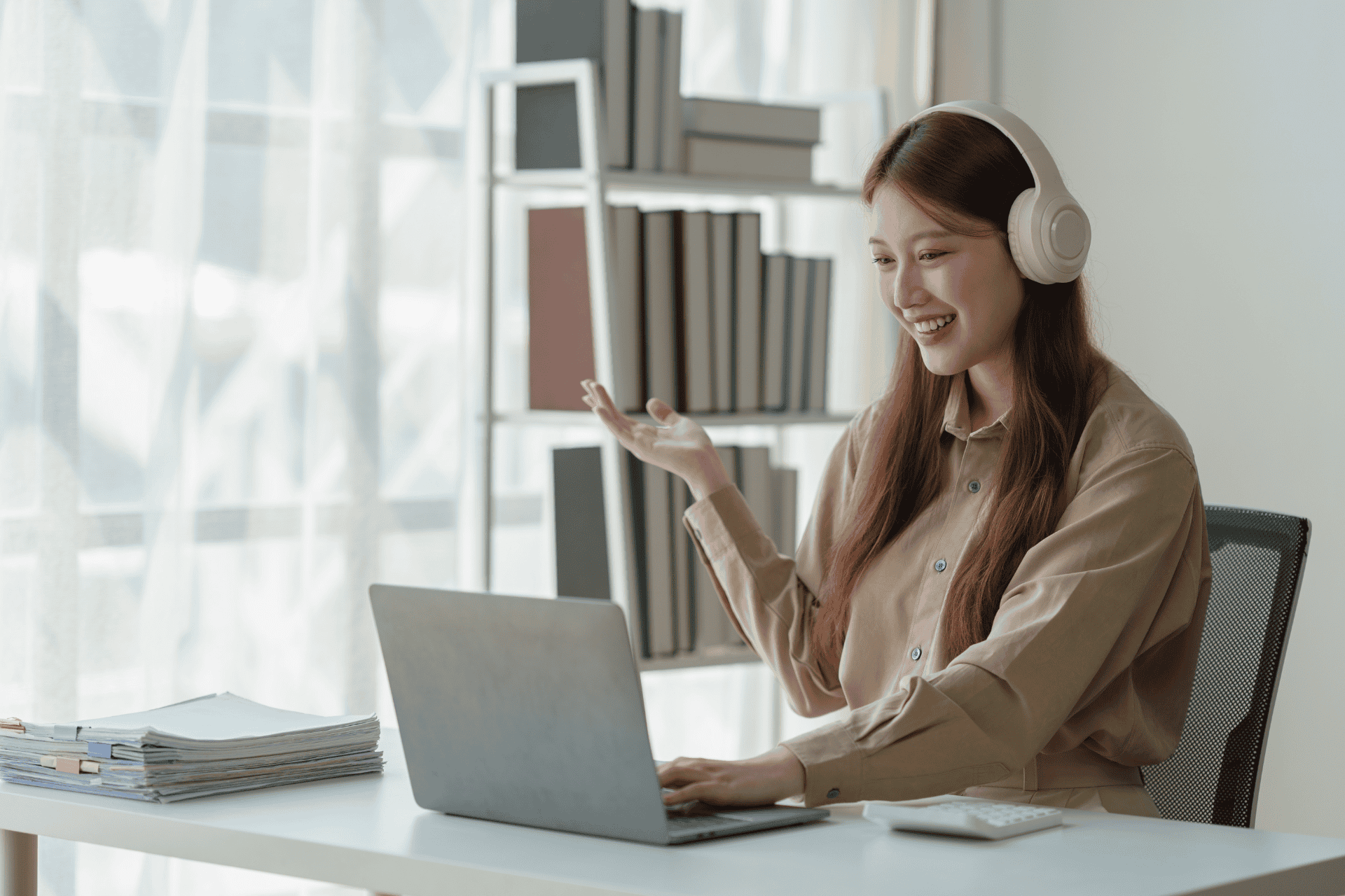 A young woman taking an online class at home, wearing headphones