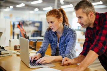 A pair of coworkers using a laptop in an office