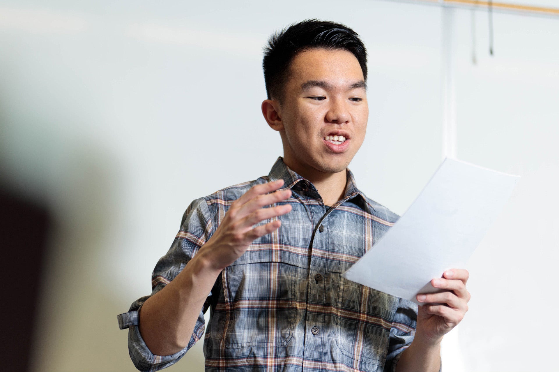 A male employee practicing pronunciation while reading from a paper