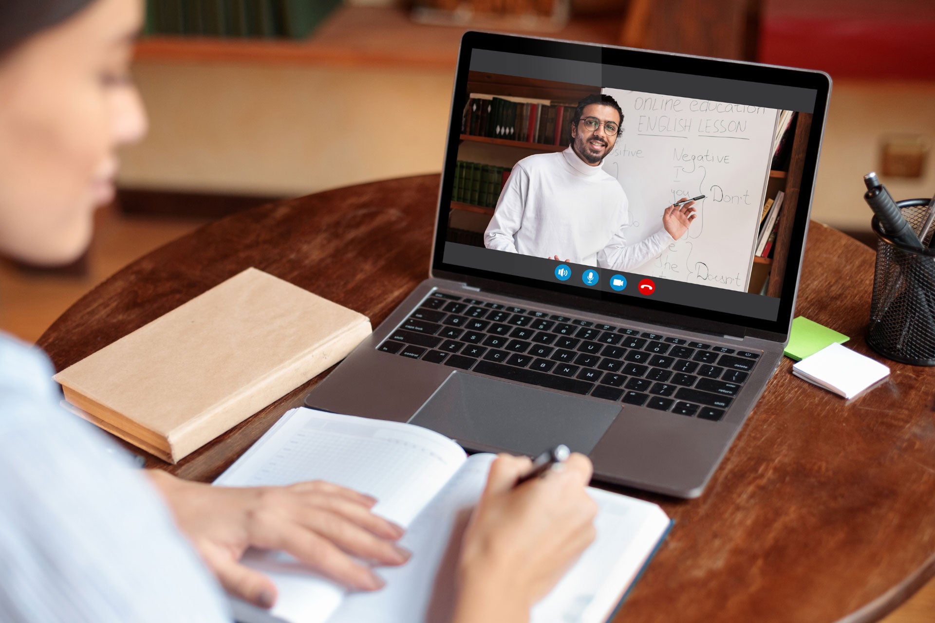 A woman sitting at a table taking an online English class on her laptop