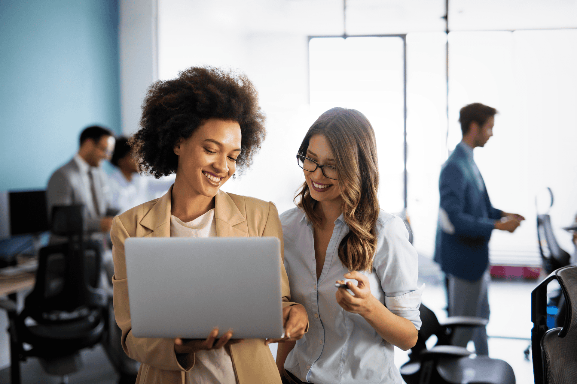 Businesswoman holding a laptop while talking to a colleague in an office